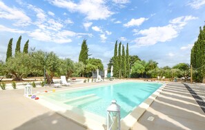 A swimming pool with lounge chairs and a lantern, surrounded by tall trees and a clear sky. - Stunning home in Menfi (Menfi)
