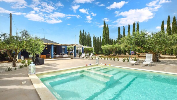 A swimming pool with a clear blue water, surrounded by lounge chairs and a covered seating area. - Stunning home in Menfi (Menfi)