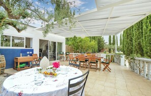 An outdoor patio with round tables and chairs, a white umbrella, and a view of the surrounding greenery. - Stunning home in Menfi (Menfi)