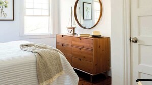 A bedroom with a bed, dresser, mirror, and ceiling fan. - Cozy 2BR/2BA Apt on Broadway (Newport)