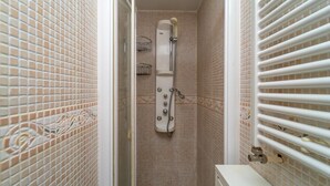 Kylpyhuone, jossa on suihku, laatoitetut seinät ja wc.