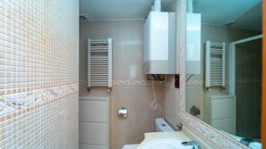 Un baño pequeño con inodoro, lavabo y toalleros.