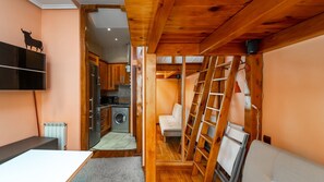 Habitació compacta i multifuncional amb bugateria, rentadora, sofà i escala.