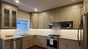 Una cocina moderna con electrodomésticos de acero inoxidable, suelo de madera y armarios de tonos claros.