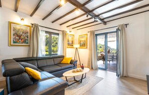 Relax in this stylish living room with a sofa, coffee table, and floor lamp, plus a sliding door leading to an outdoor space with a view.