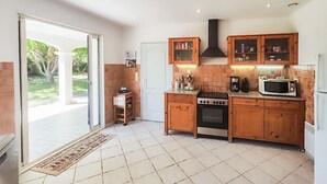 A kitchen with wooden cabinets, a stove, a microwave, and a coffee maker. There is a sliding glass door leading to a patio.