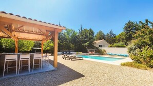 A covered outdoor area with a pool, seating, and a pergola.