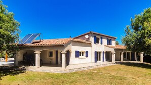 A two-story building with a tiled roof, arched doorways, and a solar panel on the roof.