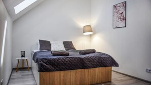 A modern bedroom with a bed, a bedside lamp, a small table, and a framed picture on the wall. - Nice home in Stare Sady with WiFi (Stare Sady)