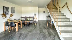A modern living room with a dining area, a sofa, and a staircase with a rope railing. - Nice home in Stare Sady with WiFi (Stare Sady)