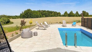 A swimming pool with lounge chairs and a covered seating area, surrounded by a field and trees. - Nice home in Stare Sady with WiFi (Stare Sady)