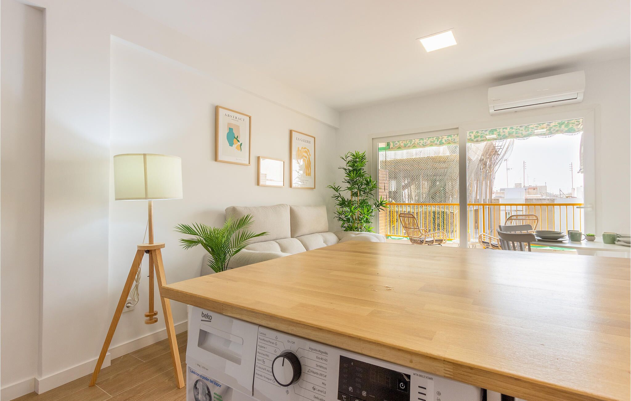 Een moderne keuken met een houten aanrecht, een ingebouwde kookplaat en een eethoek met rieten stoelen.