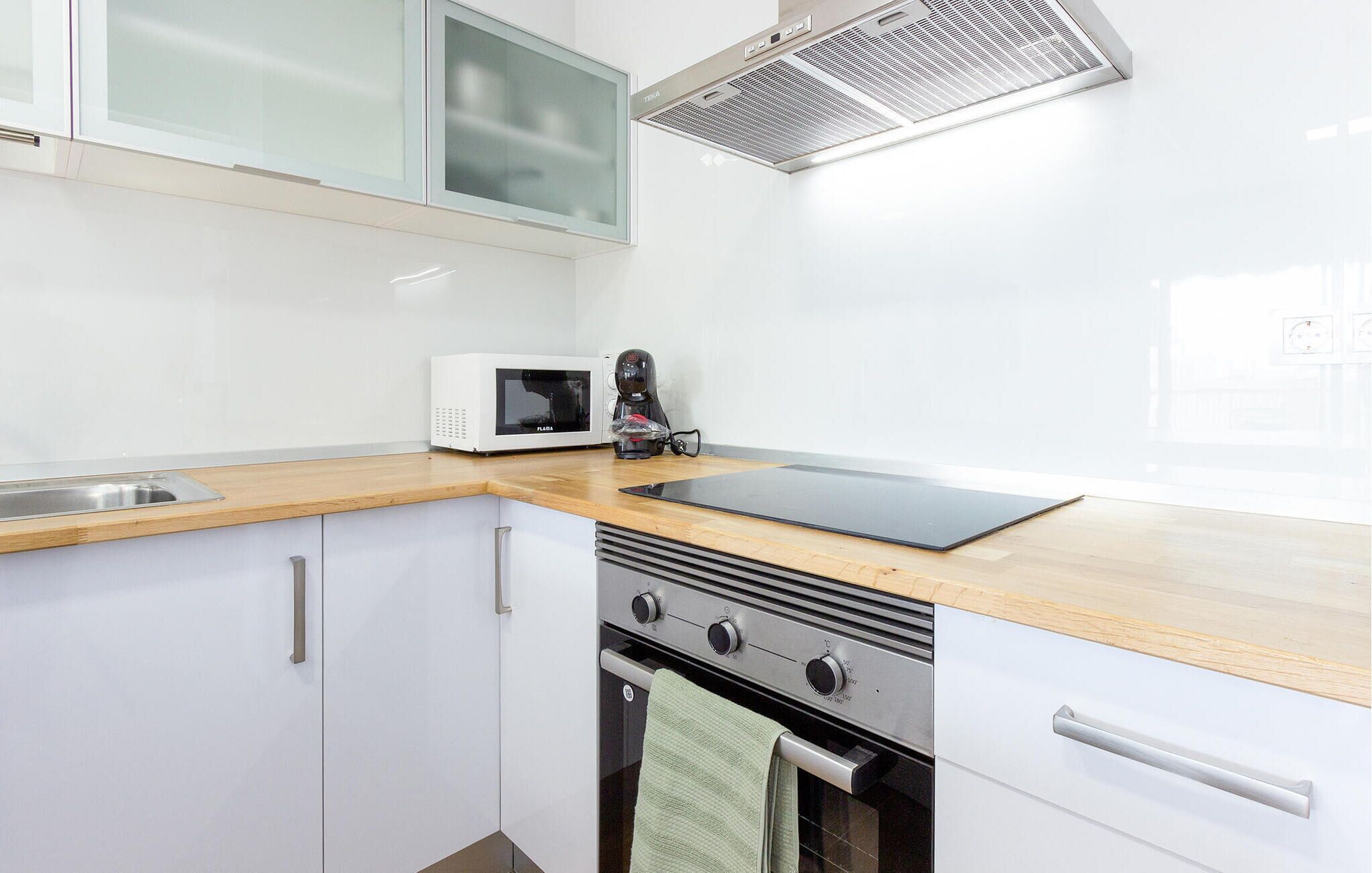 A modern kitchen with white cabinets, a microwave, a coffee maker, and a gas stove.