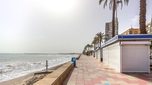 Un paseo marítimo con vista al mar, palmeras y edificios.