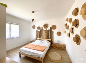 A bedroom with a wooden bed, a window, and a wall decorated with hats. - Caporizon - Villa Cosy Proche Plage Avec Grande Terrasse (Mimizan)