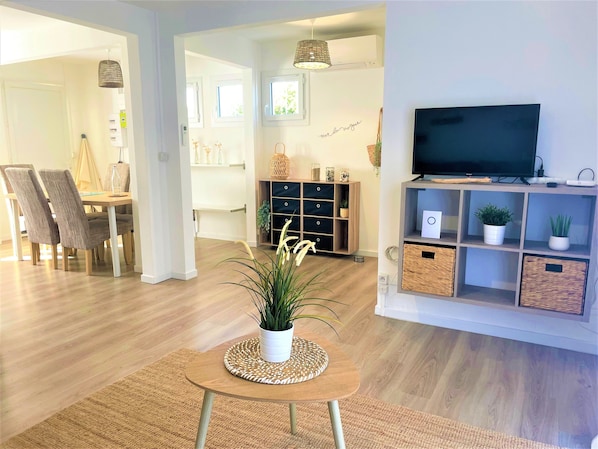 Un salon moderne avec un téléviseur, des meubles en bois et une plante en pot.