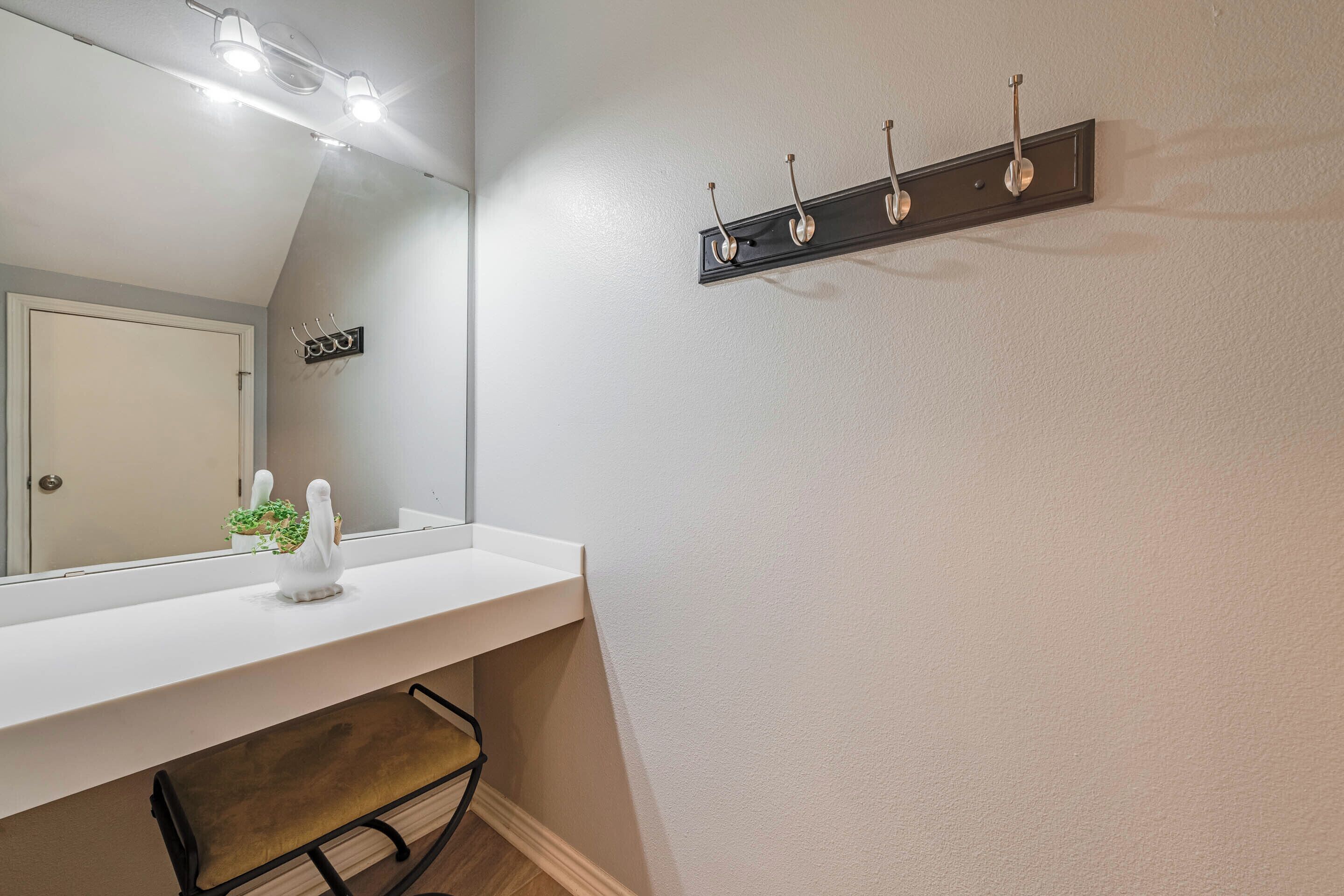 A bathroom with a white vanity, a mirror, a towel rack, and a small plant on the counter.