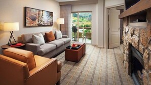 A modern living room with a sofa, armchair, and coffee table, a fireplace, and a balcony with a scenic view. - Sheraton Lakeside Terrace Villas at Mountain Vista (Avon)