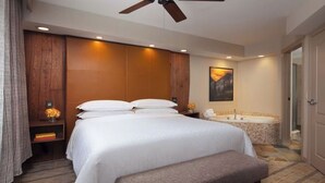 A hotel room with a large bed, a ceiling fan, a bathtub, and a painting on the wall. - Sheraton Lakeside Terrace Villas at Mountain Vista (Avon)