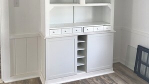 A white built-in shelving unit with multiple compartments and drawers, situated in a room with wooden flooring. - The HoneyComb - Blocks from Historic Waterfront (Beaufort)