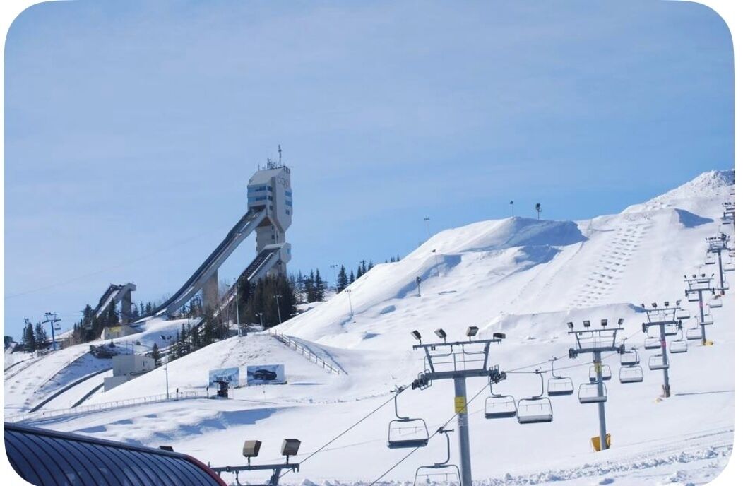 A ski lift system with chairs and a control tower on a snowy mountain slope.