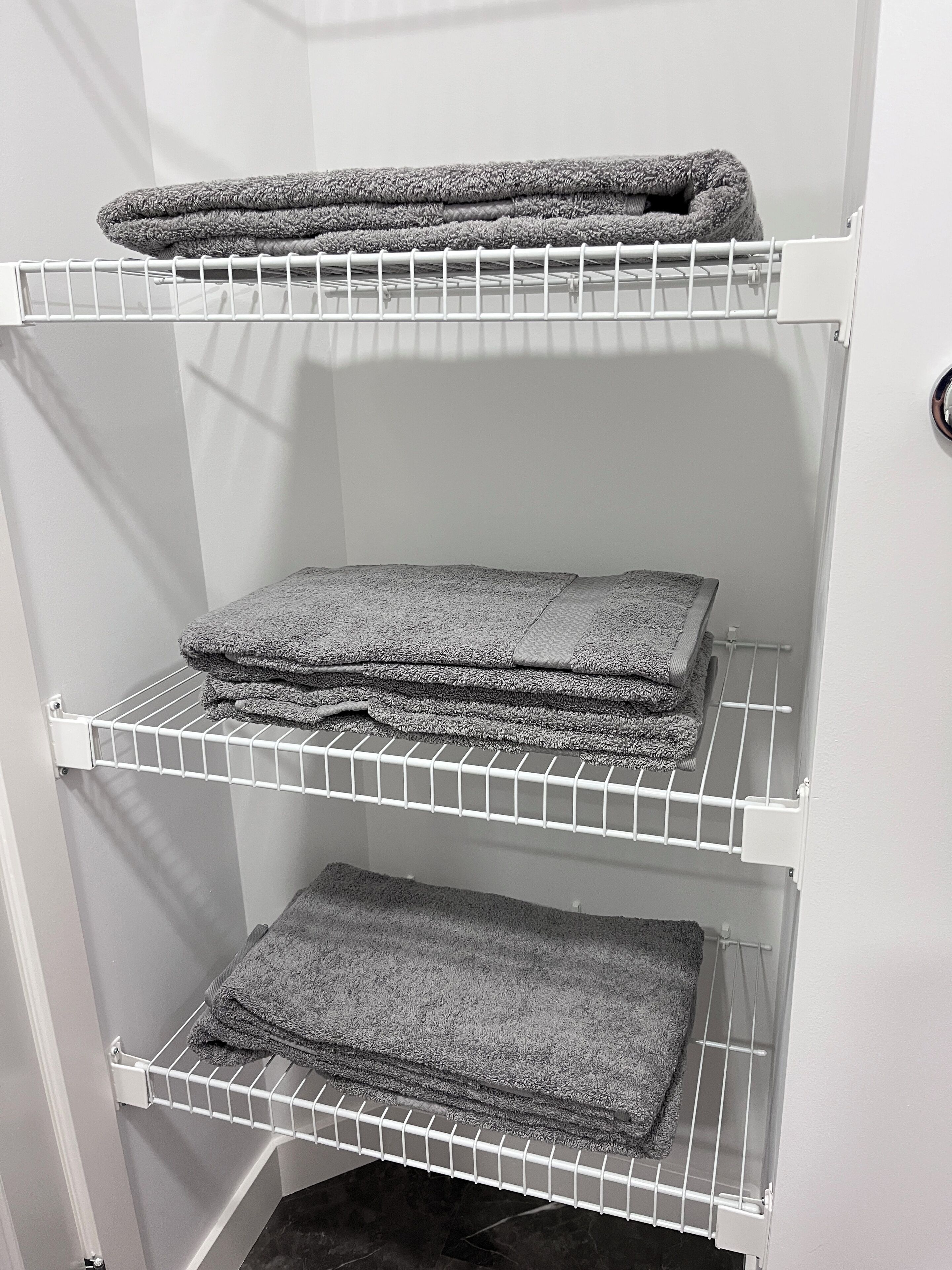 A storage unit with three shelves holding folded towels.