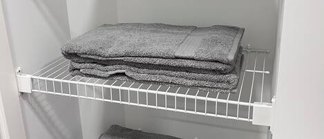 A storage unit with three shelves holding folded towels.