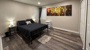 Een slaapkamer met een bed, nachtkastjes, een wanddecoratie en een deur.