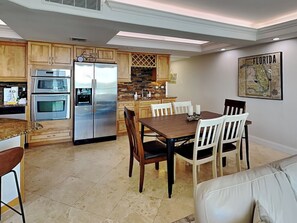 Una cocina moderna con armarios de madera, electrodomésticos de acero inoxidable y un comedor con mesa y sillas.