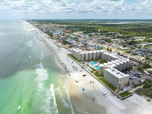 Eine Luftaufnahme eines Küstenresorts mit Strandhotels, einem Sandstrand und freier Sicht auf den Ozean.