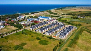 An aerial view of a residential area with multiple apartment buildings, a parking lot, and a coastline in the background. - Gorgeous apartment in Darlówko with WiFi (Darlówko)