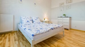 A bedroom with a bed, bedside table, lamp, dresser, and wall decorations. - Gorgeous apartment in Darlówko with WiFi (Darlówko)