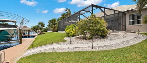 A modern outdoor area with a pool, a covered patio, and a well-maintained lawn.