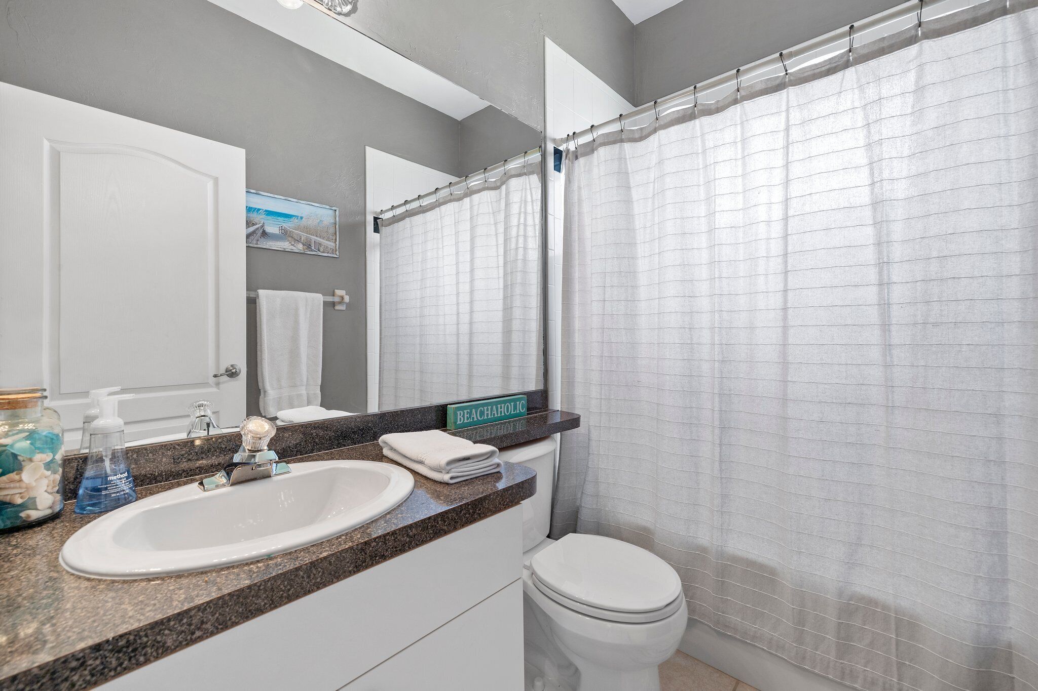 Un baño con lavamanos blanco, inodoro y cortina de ducha.