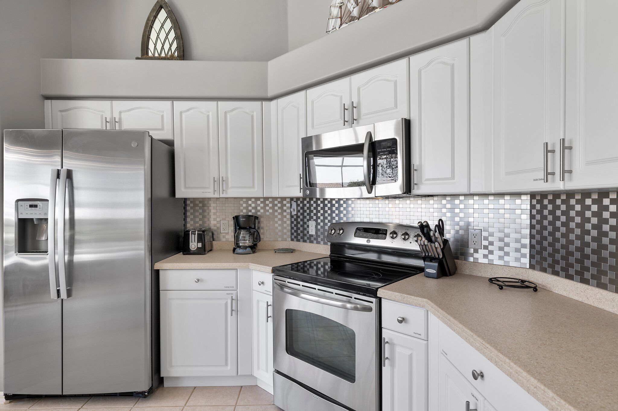 A modern kitchen with white cabinetry, stainless steel appliances, and a tiled backsplash.