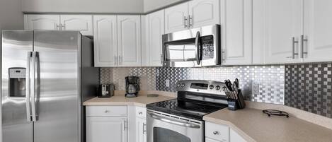 A modern kitchen with white cabinetry, stainless steel appliances, and a tiled backsplash.