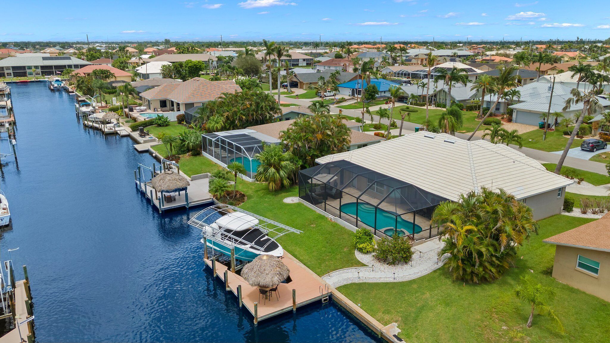 Zona residencial con un puerto deportivo, una casa con piscina y una gran estructura de vidrio.