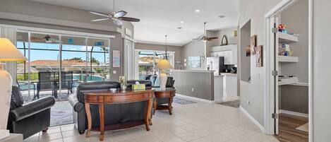 A spacious living area with a dining table, two sofas, and a ceiling fan.