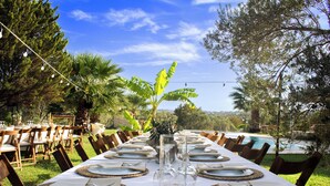 A long dining table set for a meal with a clear view of the outdoors, including trees and a pool. - Huzur villa  (Izmir)