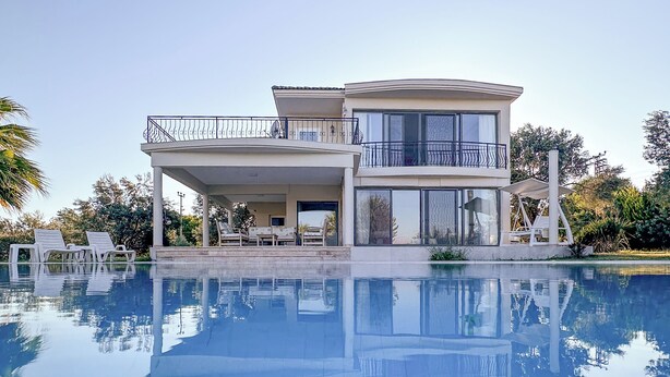 A modern two-story house with a large swimming pool in front. - Huzur villa  (Izmir)