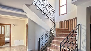 A staircase with ornate black railings and marble steps, leading to a landing with a window. - Huzur villa  (Izmir)