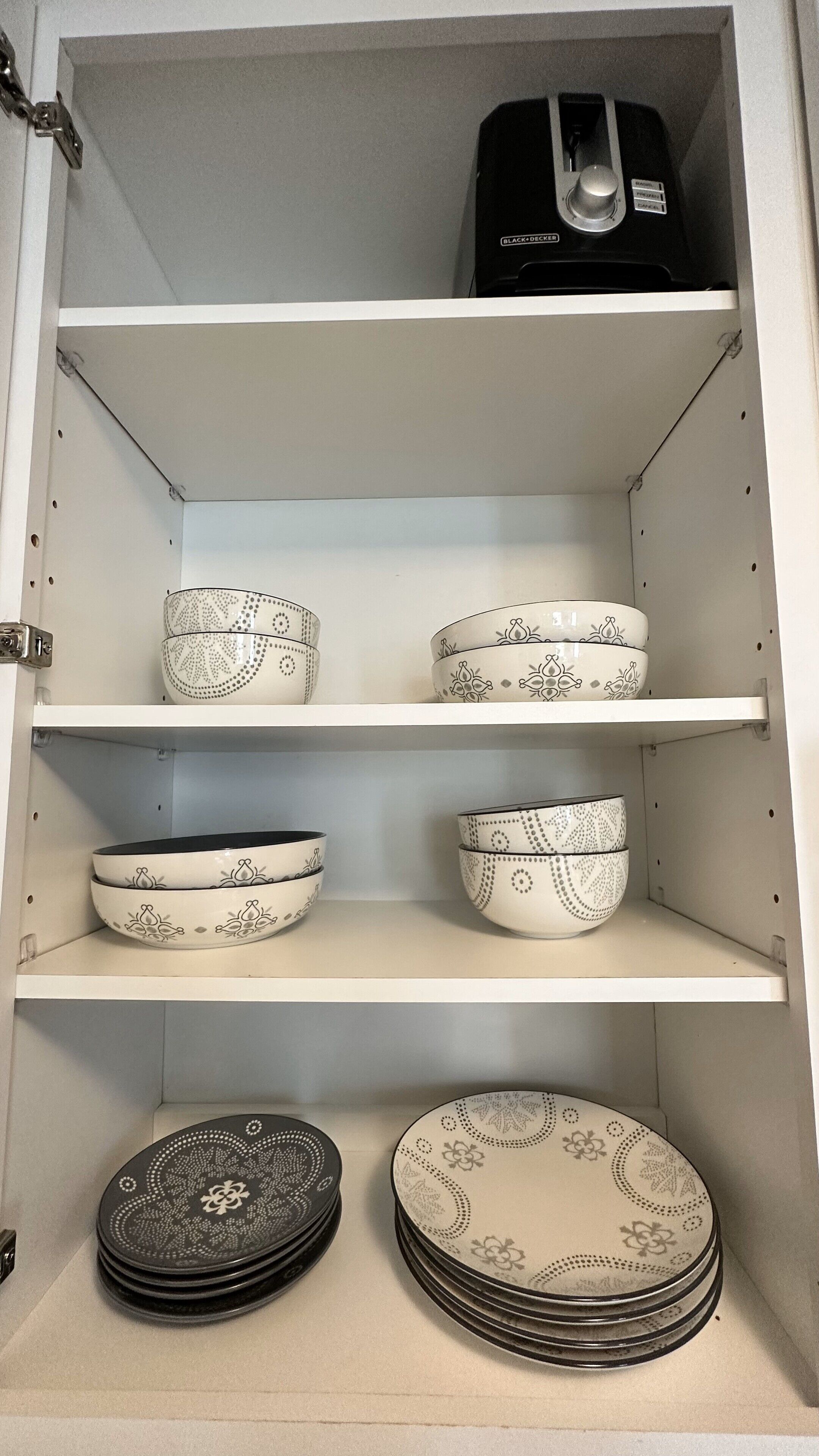 Un meuble avec trois étagères, chacune contenant différents bols et assiettes aux motifs variés.