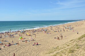 Une plage bondée où les gens se prélassent au soleil et se baignent.