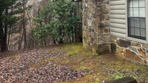 A stone chimney attached to a house with siding.