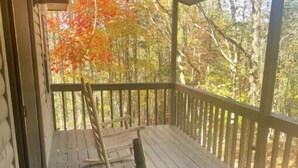 A wooden porch with a view of autumn foliage.