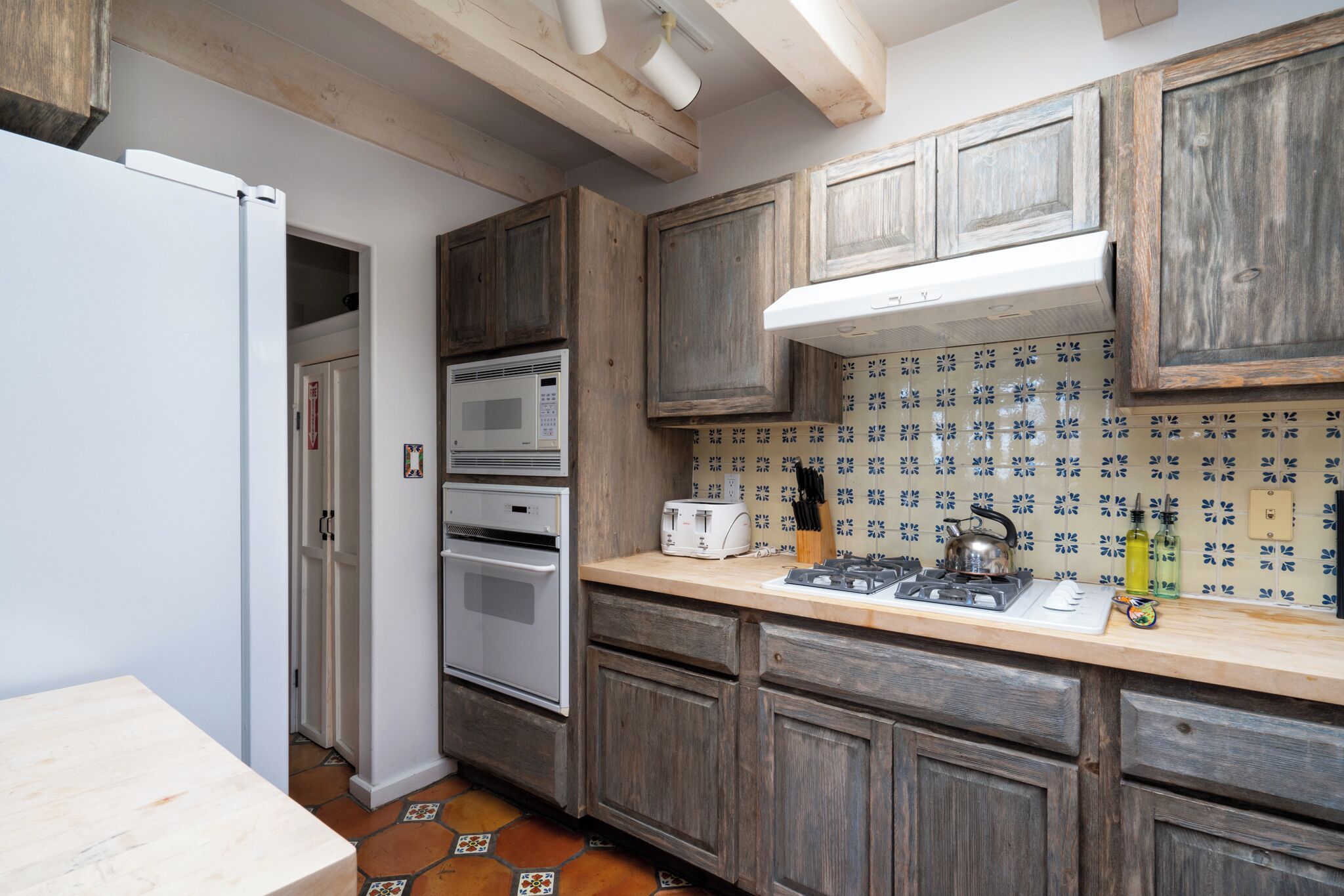 Une cuisine avec des meubles en bois, un four à micro-ondes, un four traditionnel et une cuisinière à gaz.