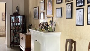 A living room with a fireplace, a wooden cabinet, and a wall adorned with framed photographs. - Mansión Serrano  (El Fuerte)