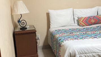 A bedroom with a bed, a nightstand, a lamp, and an air conditioner on the wall.