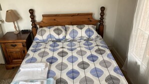 A bedroom with a wooden headboard, a bedside table with a lamp, and a patterned bedspread. - Cozy apartment in Paris (Paris)