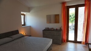Une chambre à coucher avec un lit, une commode, un miroir et une fenêtre avec des rideaux.